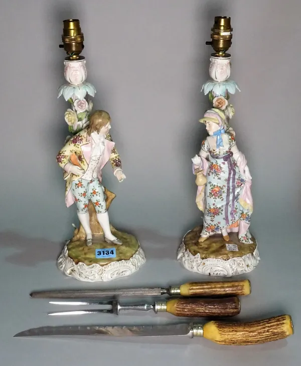 A pair of early 20th century continental ceramic figural table lamps, 38cm high, and an early 20th century antler mounted three piece carving set.