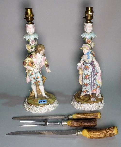 A pair of early 20th century continental ceramic figural table lamps, 38cm high, and an early 20th century antler mounted three piece carving set.
