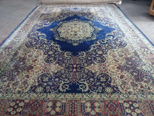 A Wilton carpet, machine made of Persian design, the dark blue field with bold centre medallion, 455cm x 320cm.