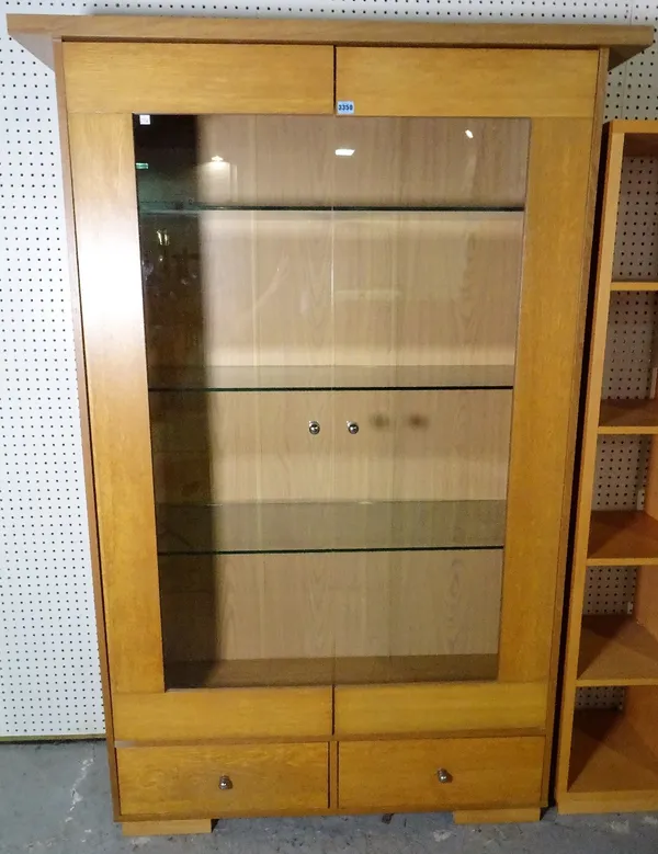 A modern hardwood floor standing display cabinet, the glass doors over two short drawers on block supports.