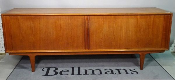 A mid-20th century teak low sideboard, with sliding doors on tapering supports, 210cm wide x 80cm high.