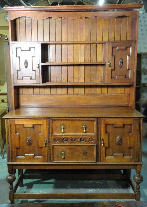 An 18th century style oak dresser, with three tier plate rack over three short drawers flanked by geometric panelled doors, 136cm wide x 202cm high.