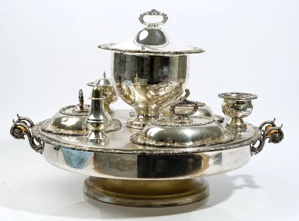 A plated dining table twin handled rotating centrepiece food stand, comprising; a lidded soup tureen, three shaped oval lidded entree dishes, a pepper