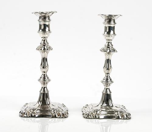 A pair of William IV silver table candlesticks, in an 18th century design, each with a shaped stem, raised on a shaped square base, the tops with deta