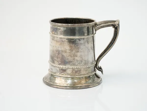 An Omar Ramsden silver mug, of tapered cylindrical form, raised on a flared circular foot, the curved angular handle having a shield shaped terminal,