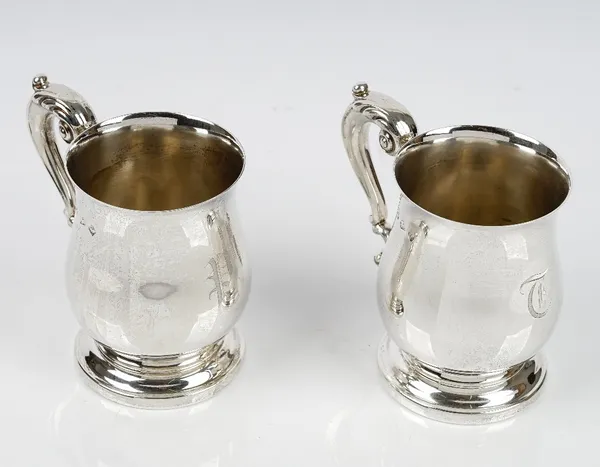 A pair of silver mugs, each of baluster form, having a foliate capped scrolled handle and raised on a circular foot, Birmingham 1979, height 12cm, com