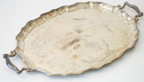 A silver twin handled shaped oval tray, presentation inscribed to the centre within a Chippendale style rim, raised on four bun feet, detailed Birks S