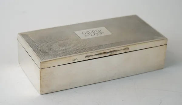 A silver rectangular table cigarette box, wooden lined within, the hinged lid with a monogram engraved rectangular cartouche on an engine turned groun