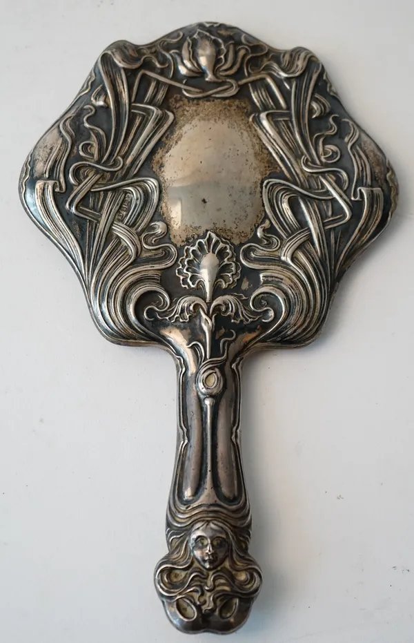 A lady's silver mounted Art Nouveau decorated hand mirror, the handle with a female face mask with flowing hair, the mirror back decorated with flowin
