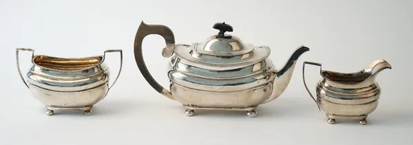 A silver three piece tea set, comprising; a teapot with black fittings, a twin handled sugar bowl and a milk jug, each piece of compressed curved form