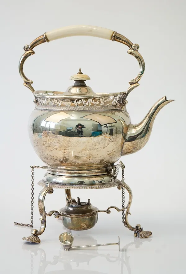 A silver tea kettle, stand and burner, the top of the kettle with scroll pierced decoration above a gadrooned border, with a tripod burner stand raise
