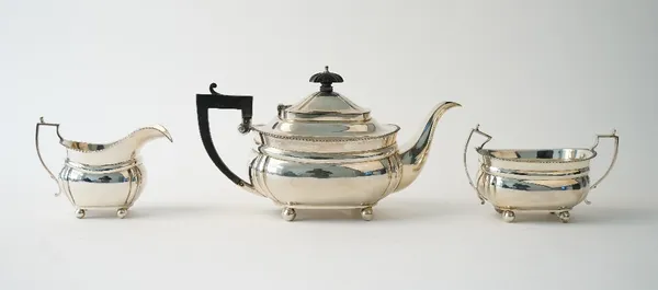 A silver three piece tea set, comprising; a teapot with black fittings, a twin handled sugar bowl and a milk jug, each piece of curved panelled form,