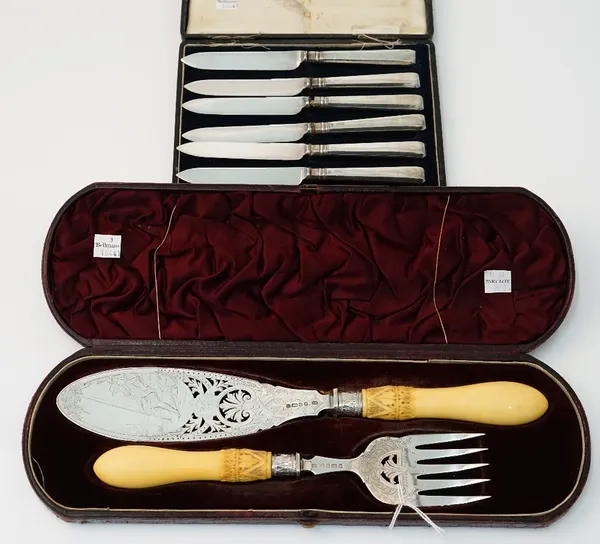 A pair of Victorian silver fish servers, with pierced and engraved decoration of a fisherman seated beside the bank, Sheffield 1883, with carved ivory