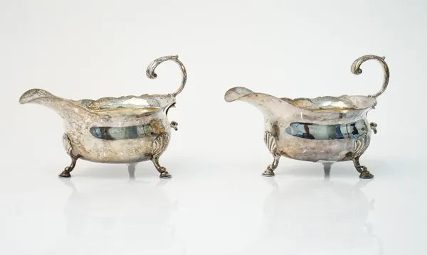 A George III pair of silver sauceboats, each having a shaped rim, scrolled handle and raised on three pad feet, London 1782, maker David Hennell I.