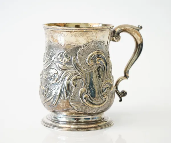 A George II silver mug, of baluster form, with later foliate and scroll embossed decoration, scrolling handle, raised on a circular foot, London 1748,