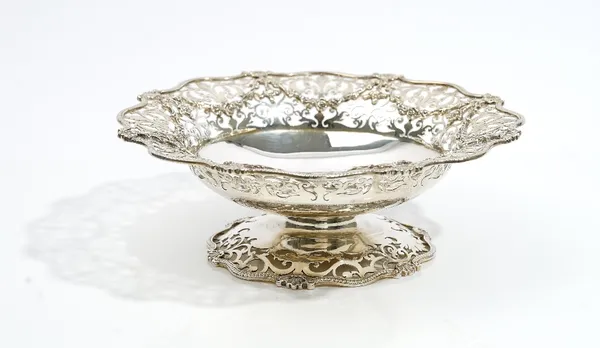 A silver pedestal bonbon dish, of shaped circular form, the flared rim cast and pierced with floral festoons and scroll work, the border with scallop