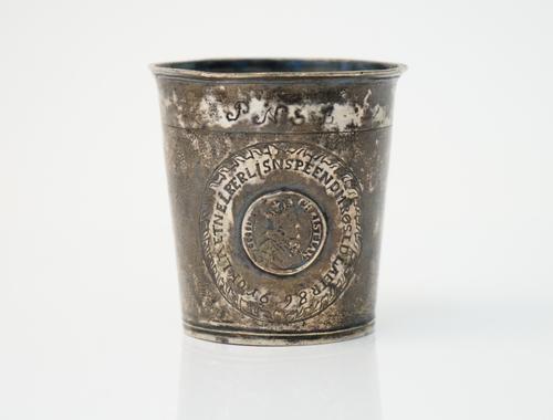 A North European beaker, of tapered cylindrical form, the body mounted with a Denmark Christian IV silver half krone 1624, height 8cm, weight 99 gms.