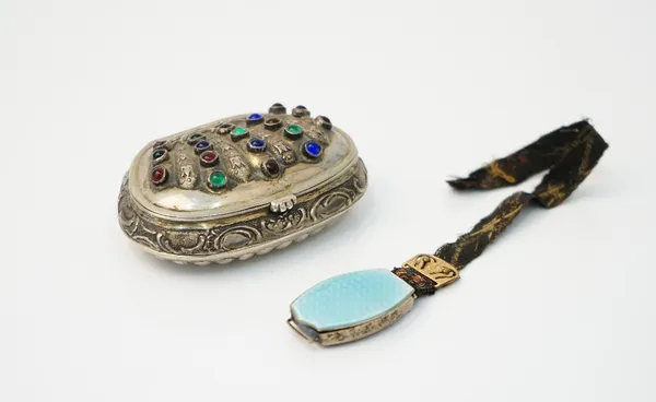 A European shaped oval hinge lidded snuff box, with scroll and partly fluted decoration, the hinged lid mounted with blue, green and red cabochon gems