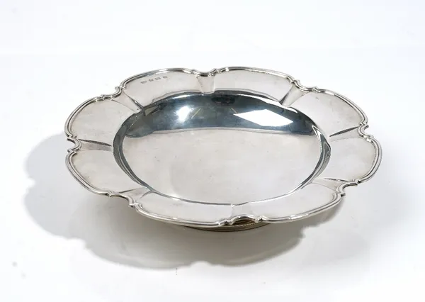 A silver dish, of shaped circular form, having a panelled rim, raised on a circular foot, diameter 23cm, Birmingham 1936, weight 335 gms.