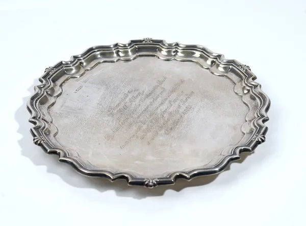 A silver salver, of shaped circular form, having a Chippendale style rim, raised on three feet, presentation inscribed to the centre, diameter 26.5cm,