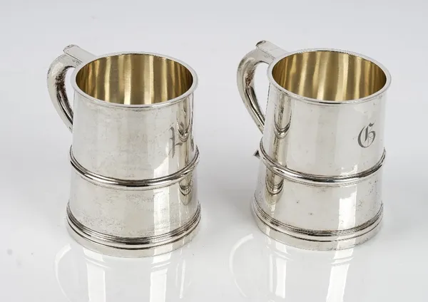 A pair of silver mugs, each of tapered cylindrical form in the 18th century taste, the handles having heart shaped terminals, London 1942, height 10cm