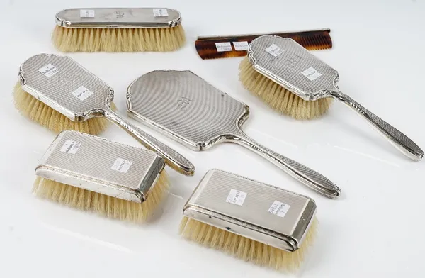 A pair of silver mounted rectangular hairbrushes, Birmingham 1962 and a silver mounted five piece composite dressing set, comprising; a hand mirror, a