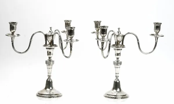 A pair of Portuguese three light table candelabra, each having scrolling arms and circular drip pans to the three lights, otherwise decorated with ree