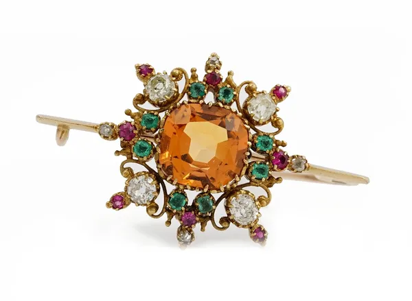 A late 19th/early 20th entury topaz, emerald, ruby and diamond brooch, the central cushion cut topaz claw set in a surround of rectangular, and circul