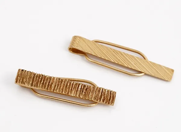 A Kutchinsky 9ct gold tie slide, with bark textured decoration, London 1970 and another Kutchinsky 9ct gold tie slide, decorated with engine turned ba