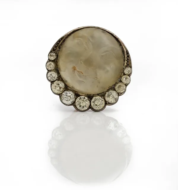 A rock crystal and colourless paste set brooch, the circular cabochon rock crystal carved to depict the Man in the Moon, in a foiled closed-back setti