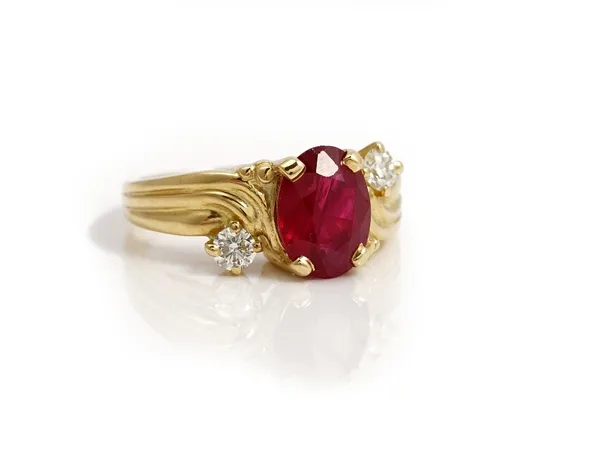 A gold, ruby and diamond three stone ring, claw set with an oval cut ruby between two circular cut diamonds, in a twist design, detailed 18 CT, ring s