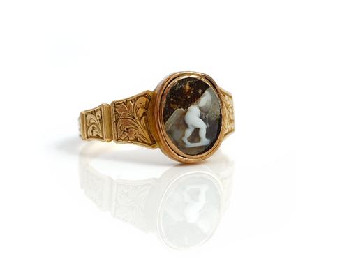 A Victorian gold and oval cameo ring, the mount decorated with engraved tapered panels, (the central cameo badly damaged), circa 1850, ring size K and