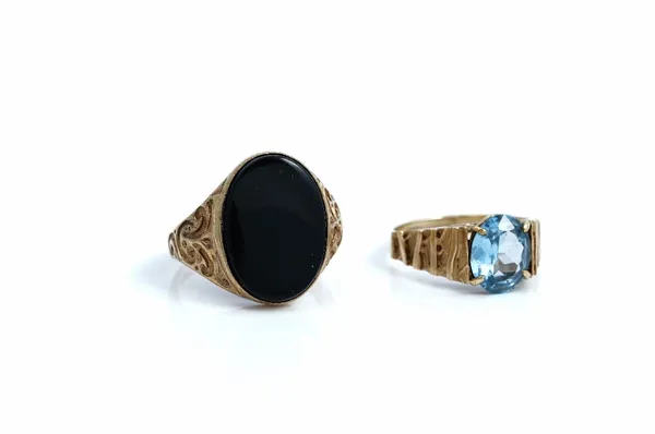 A gold and oval black onyx signet style ring, having scroll decorated shoulders, ring size S and a 9ct gold ring, claw set with an oval cut synthetic