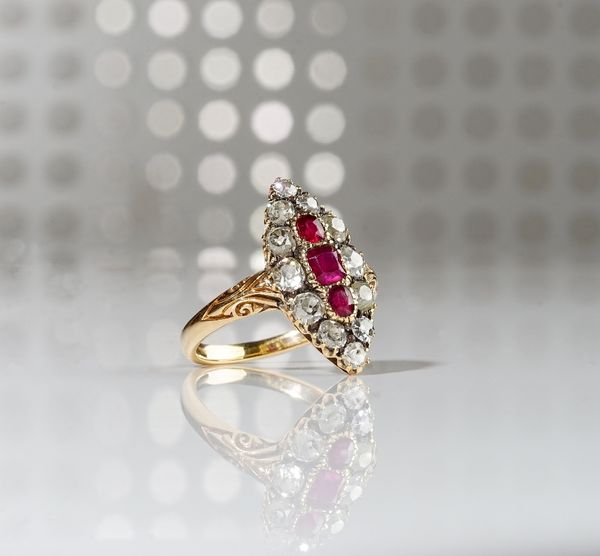 A gold, ruby and diamond set marquise shaped cluster ring, mounted with three cushion shaped rubies to the centre, in a surround of twelve cushion sha