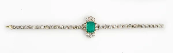 An emerald and diamond bracelet mounted with the cushion cut emerald to the centre, between two rows of three cushion shaped diamonds and with a pair