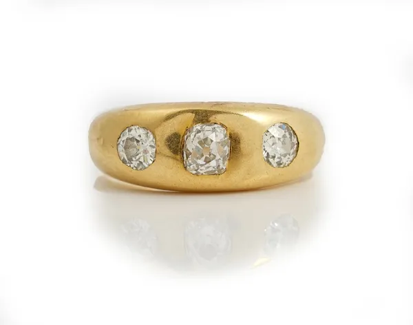 An 18ct gold and diamond three stone ring, gypsy set with a row of cushion shaped diamonds, London 1917, ring size R 1/2, gross weight 8.7gms.