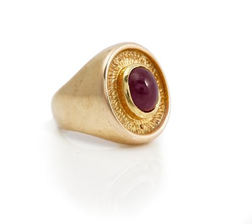 A 9ct gold and cabochon ruby single stone ring, mounted with an oval cabochon ruby, the mount otherwise with an oval bark textured surround, ring size