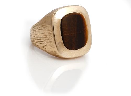 A gold and tiger's eye gentleman's signet ring, mounted with a curved rectangular tiger's eye, the mount otherwise with bark textured decoration, ring