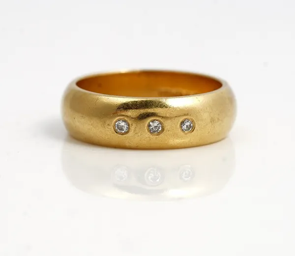 An 18ct gold  and diamond set band ring, gypsy set with a row of three circular cut diamonds, ring size M, gross weight 7.9 gms.
