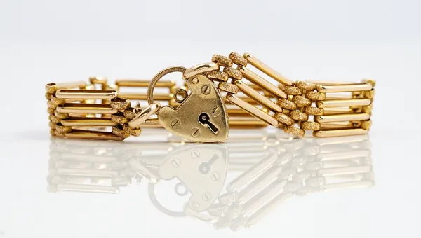 A gold decorated and plain bar and oval link gate bracelet, detailed 15 C, weight 12.7 gms, on a later gold heart shaped padlock clasp, detailed 9 CT,