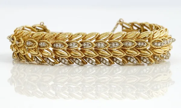 A gold and diamond bracelet, in a multiple row foliate design, mounted with circular cut diamonds, on a snap clasp, fitted with a safety chain, appare