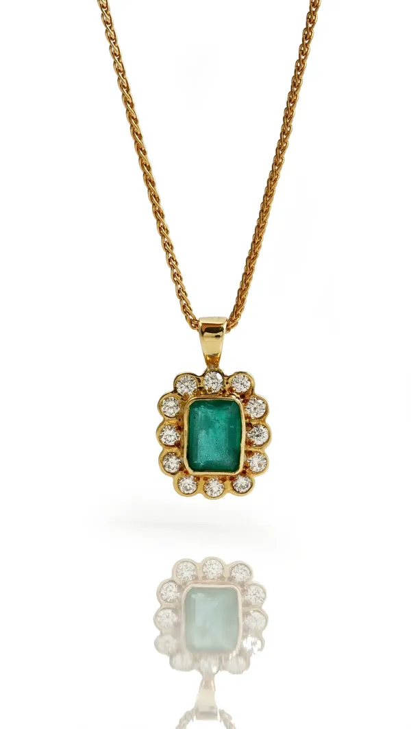 An 18ct gold, emerald and diamond cluster pendant, mounted with the rectangular step cut emerald in a surround of circular cut diamonds, with a gold n