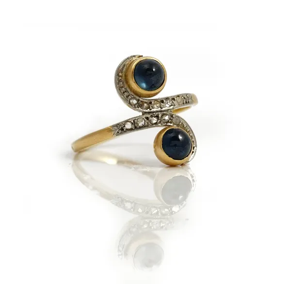 A French diamond and sapphire ring, mounted with two cabochon sapphires and otherwise set with rose cut diamonds in a twistover design, ring size P an