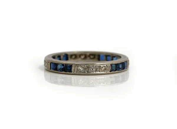 A platinum, sapphire and diamond full eternity ring, mounted with rows of three circular cut diamonds, alternating with rows of three square cut sapph