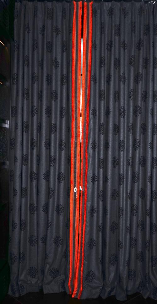 A pair of dark heather grey wool fabric curtains with black embroidered medallions, trimmed with charcoal and orange bandings. 90cm wide x 310cm long.