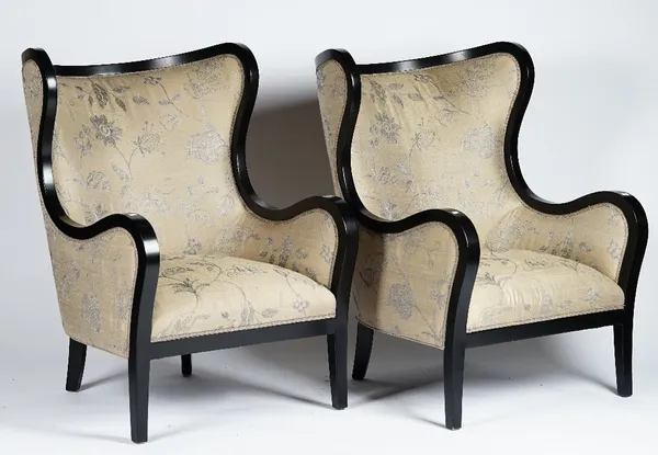 A pair of contemporary wing armchairs with ebonised frames, upholstered in greige silver embroidered fabric, 77cm wide x 111cm high, (2).