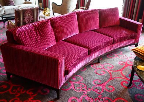 A contemporary curved three seat sofa, upholstered in striped black and magenta with loose back and seat cushions, with faux rosewood frames, with one
