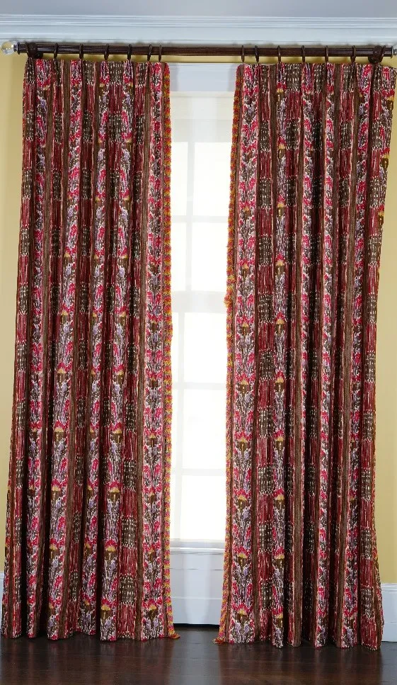 A pair of linen curtains printed with multicoloured designs, with tasseled edging. 85cm wide x 310cm long.