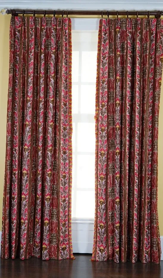 A pair of linen curtains printed with multicoloured designs, with tasseled edging. 85cm wide x 310cm long.