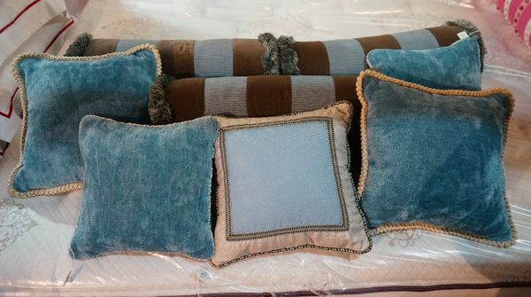 A group of cushions, including three bolsters banded in brown velvet and five other blue and cream cushions (8).